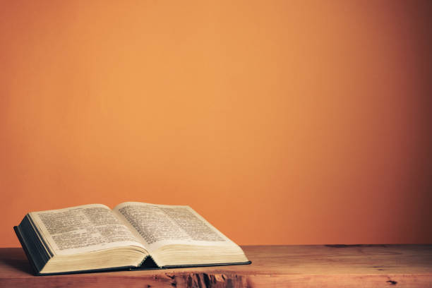 istock Open Holy Bible on a old wooden table. Beautiful orange wall background. 1267274754