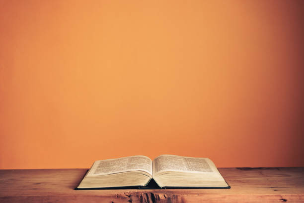 open holy bible on a old wooden table. beautiful orange wall background. - book school desk old imagens e fotografias de stock