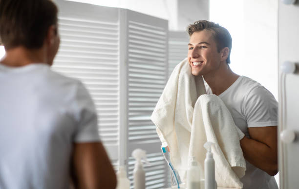 pewny siebie młody człowiek patrzący w lustro z ręcznikiem - men shaving human face bathroom zdjęcia i obrazy z banku zdjęć