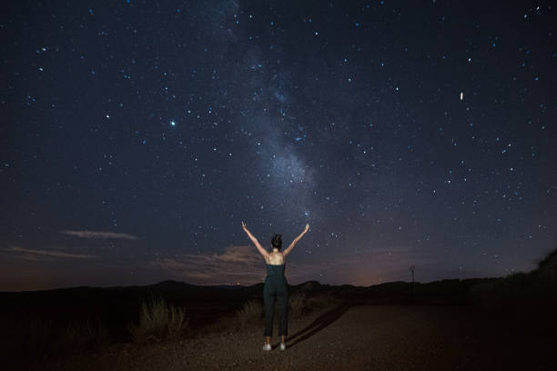 istock Woman with arms raised by a starry sky with a visible Milky Way 1267277488