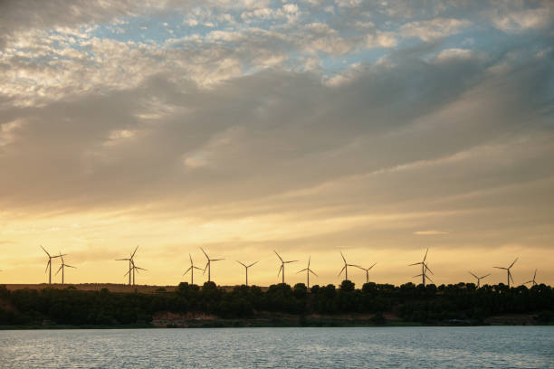 istock Wind turbines by a lake at sunset 1267277564