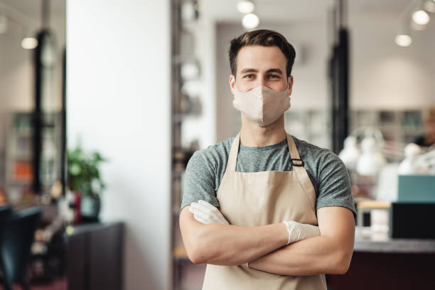 istock Young male barber meeting clients in protective mask, empty space 1267277692