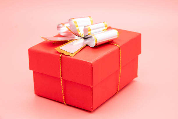 istock Red gift box with white ribbon and presents on pink background. 1267277730