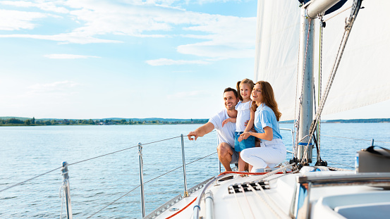 Parents And Daughter Sitting On Yacht Deck Sailing Across Sea Enjoying Summer Vacation Outside. Panorama, Free Space