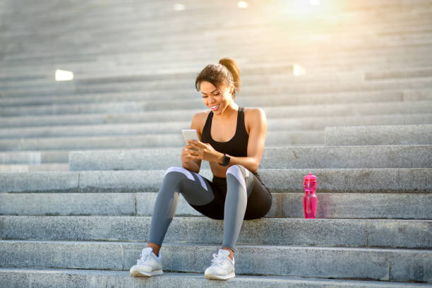 istock Sporty black girl in using phone while resting 1267278709