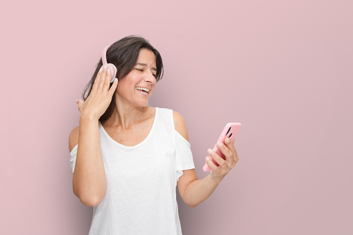 Attractive Spanish middle-aged brunette woman making expressive gestures. enjoying music and the phone