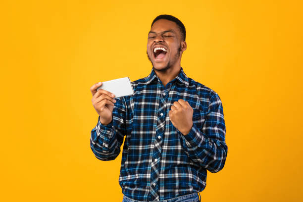 istock Joyful Black Man Holding Smartphone Shouting Shaking Fists In Studio 1267280239