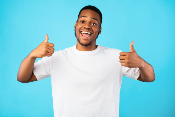 istock Black Millennial Guy Gesturing Thumbs-Up With Both Hands, Blue Background 1267280383