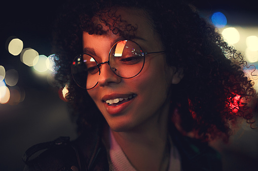 Portrait of young cute curly afro american girl. Night city lights. Neon illumination