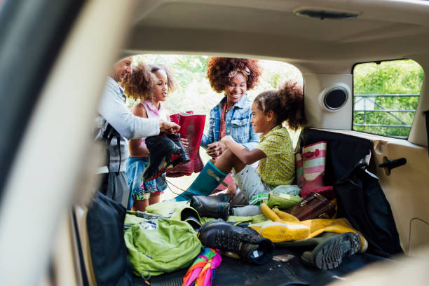 Family Unpacking The Car A shot of a caucasian male in his 50's with his black wife and mixed-race children unpacking the car ready for their walk in the countryside. northern europe family car stock pictures, royalty-free photos & images
