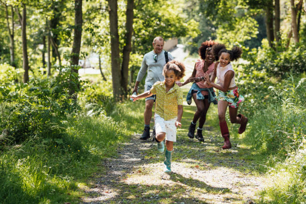 Walking Together As A family A shot of a diverse family with a caucasian male in his 50's and black female in her 40's and two mixed-race children walking in the countryside. life balance photos stock pictures, royalty-free photos & images