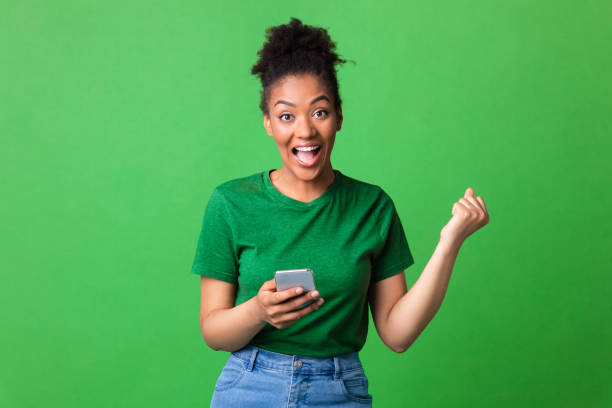 istock Excited afro girl feeling ecstatic holding phone 1267283100