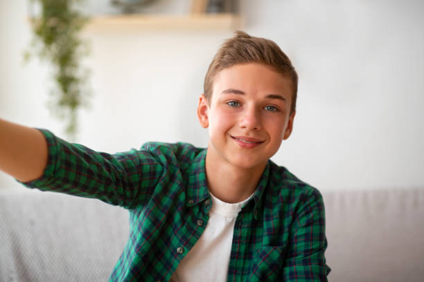 istock Handsome teen boy taking selfie while spending time at home 1267284202