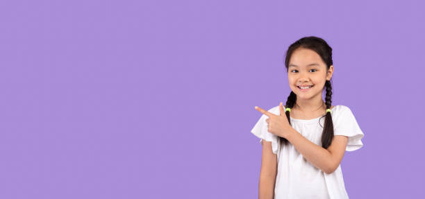 istock Cute Asian Little Girl Pointing Finger Aside In Studio, Panorama 1267285414