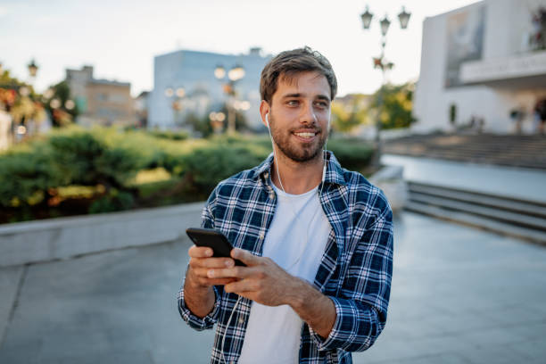 istock Happy millennial guy using mobile phone with headphones, starting a video call 1267287021