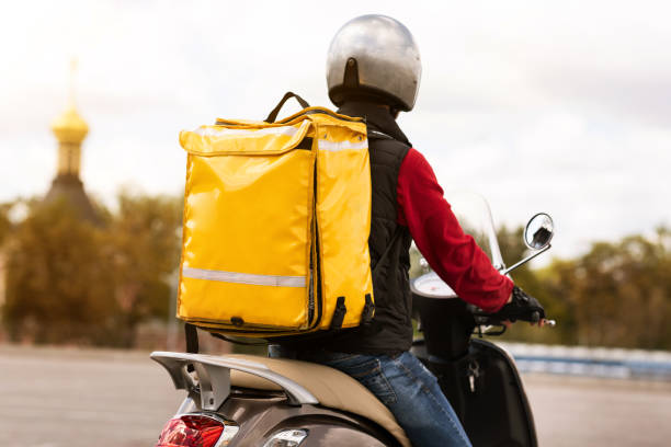 istock Courier With Yellow Backpack Delivering Meals On Scooter Outside, Rear-View 1267287382
