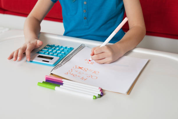 istock Midsection of a girl writing in book doing homework 1267287414