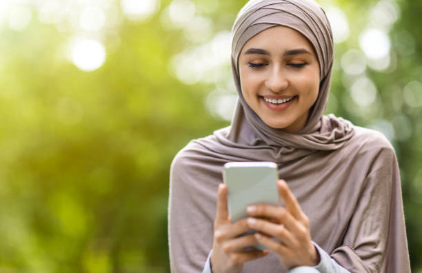 istock Beautiful arab girl using modern smartphone, park background 1267289393