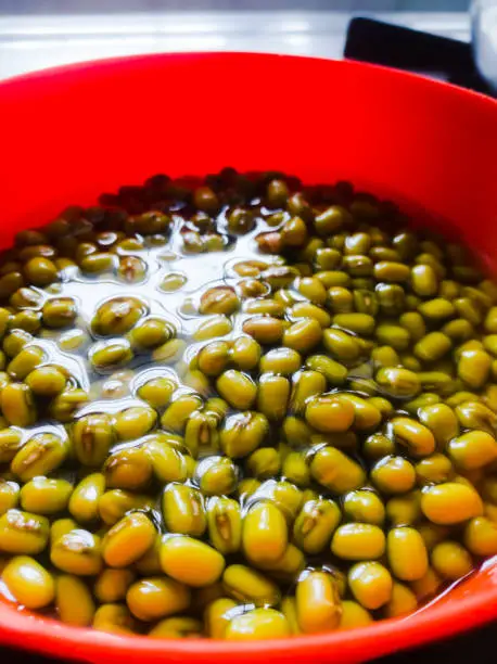 Photo of Green gram placed in soaked condition for sprouting in an orange bowl.