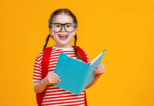 aluna alegre sorrindo e lendo livro didático - child glasses elementary student reading - fotografias e filmes do acervo