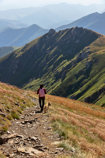 Man climbing to the top of a mountain Coriscao with a dog in Leon in a sunny day, Spain