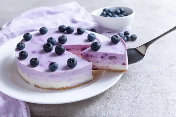 Photo of Vanilla blueberry cheesecake decorated with fresh berries on a gray table