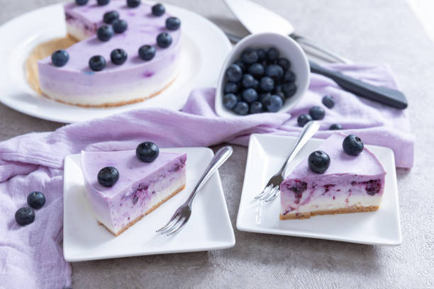 Vanilla blueberry cheesecake decorated with fresh berries on a gray table