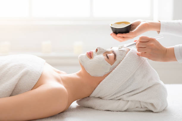 istock Beautician applying white mud mask on woman face 1267292603