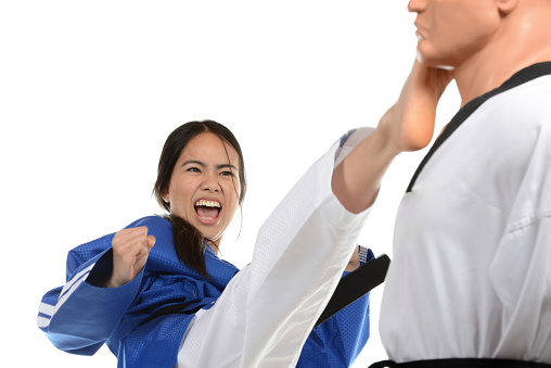Martial artist kicking a training mannequin in the face.