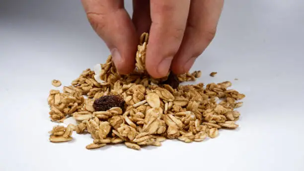 Photo of grabbing a pinch of healthy granola cereal on white background