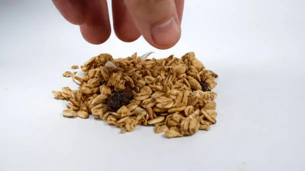 Photo of Picking up of healthy granola cereal on white background