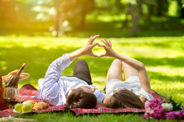 istock Affectionate young couple making heart with their hands while lying on picnic blanket at park 1267293450