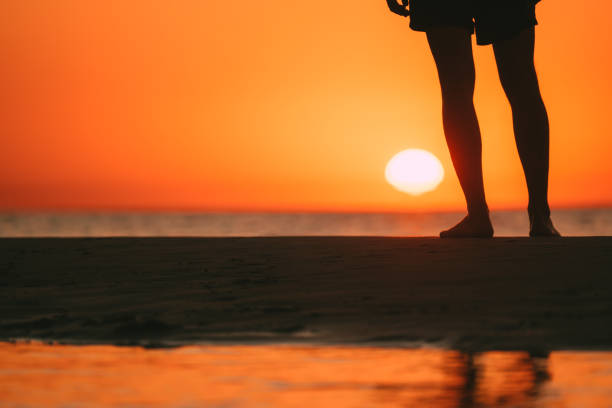 istock Man's feet at sunset beach. Close up 1267300255