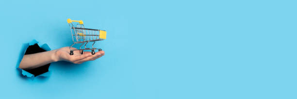 istock Woman's hand on the palm holds a trolley on a bright blue background. Banner. 1267303772