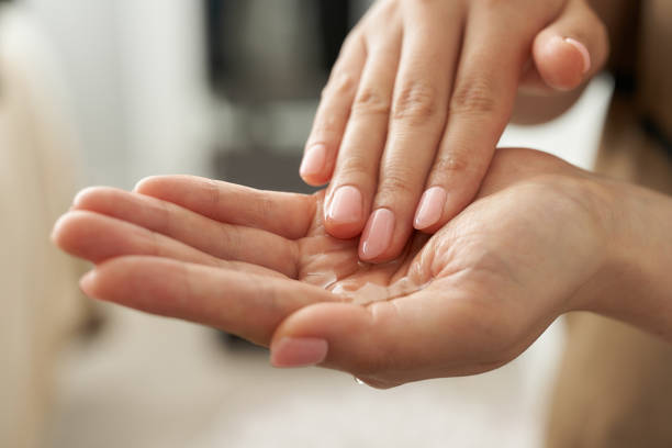 estetista giapponese che tiene un olio da massaggio in mano - olio per massaggi foto e immagini stock