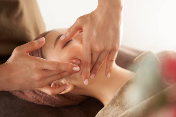 donna giapponese che riceve un massaggio facciale in un salone estetico - trattamento di benessere foto e immagini stock