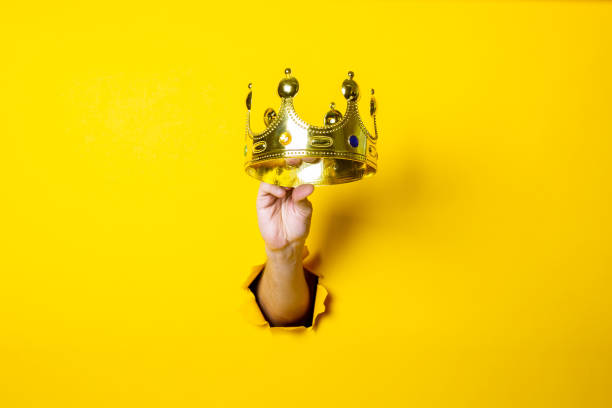 istock Female hand holds a gold crown on a bright yellow background. 1267306317