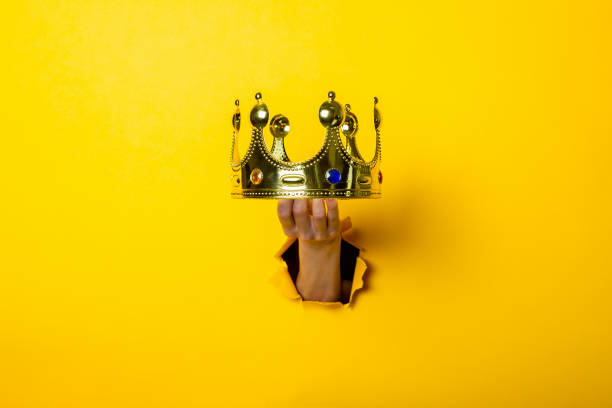 istock Female hand holds a gold crown on a bright yellow background. 1267306466