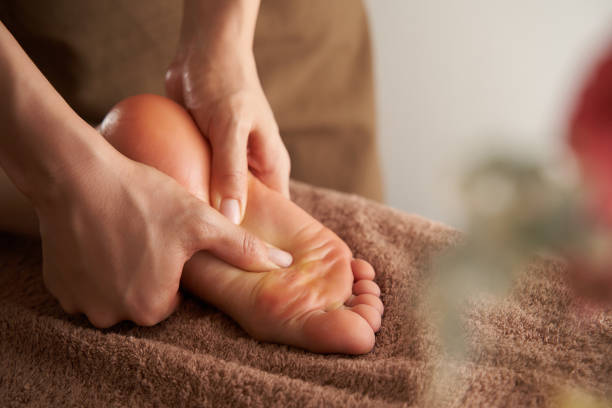 una donna giapponese riceve un massaggio ai piedi in un salone di bellezza - olio per massaggi foto e immagini stock
