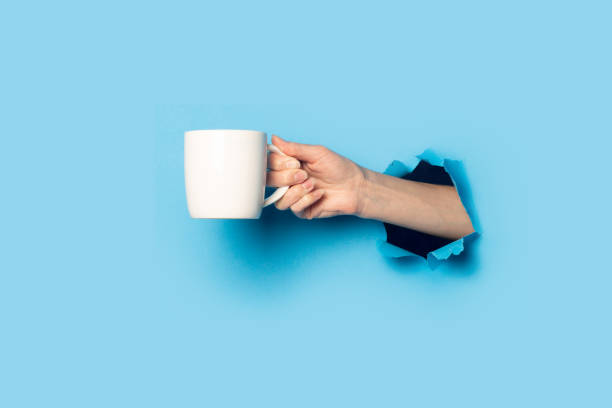 istock Female hand holding a white cup on a bright blue background 1267306563
