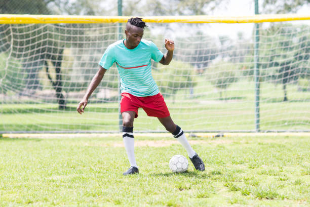 fußballer, der den ball auf einem fußballplatz kickt. - sport university football player action stock-fotos und bilder