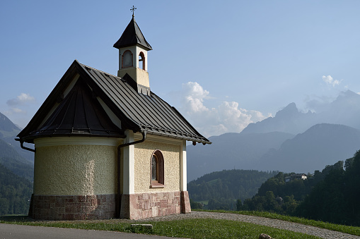 Kirchleitn chapel and Mt. Watzmann on a summer day with blue sky. Religious building and beautiful alpine landscape in national park Berchtesgadener Land, Bavaria, Germany.