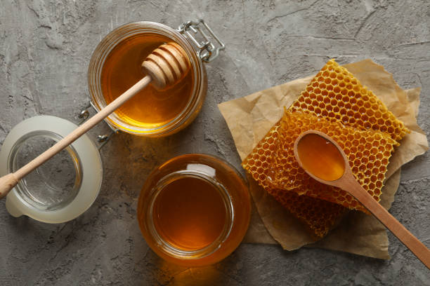 istock Composition with honeycombs, honey and jars on gray background 1267308459