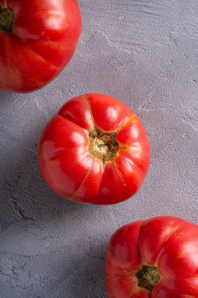 trois légumes roses de tomate d’héritage dans la rangée, tomates mûres rouges fraîches, nourriture végétalienne, fond en béton de pierre, vue supérieure - tomato beefsteak tomato heirloom tomato pink photos et images de collection