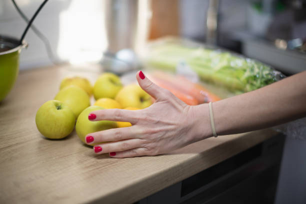 istock Female hand holding yellow apples on kitchen counter 1267310017