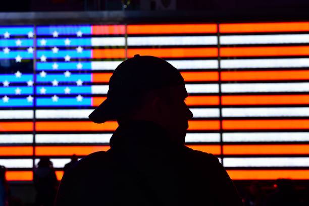 istock Silhouette Man Against Illuminated American Flag 1267312496