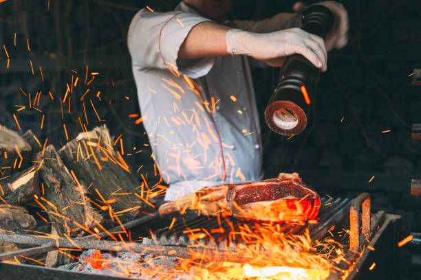 istock Cooking Steak in a stone oven. Chef pepper the steak on fire. 1267314163