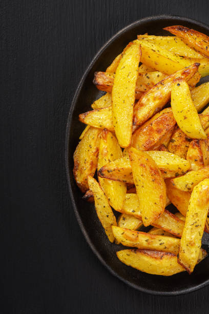 istock Fried potatoes in a rural style, with spices. On rustic pan, on a wooden black table 1267314212