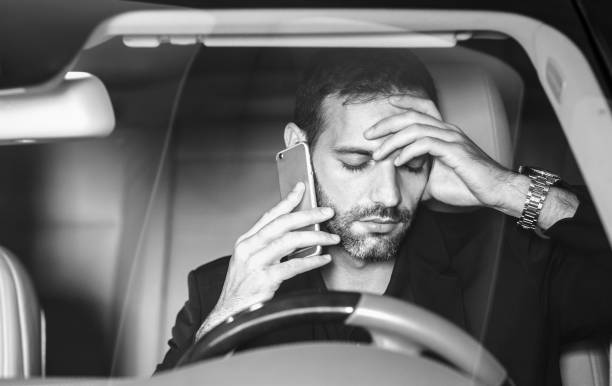 hombre estresado conduciendo y hablando por teléfono en el coche después del trabajo. - overworked worried distraught front view fotografías e imágenes de stock