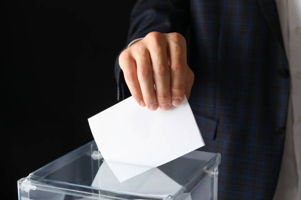 istock Man putting ballot into voting box on black background 1267314512